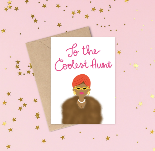 White card with the words To the Coolest Aunt written in pink cursive with a brown skinned woman wearing a fur jacket, pearls, an orange turban and yellow cat eye glasses and pink lip stick.