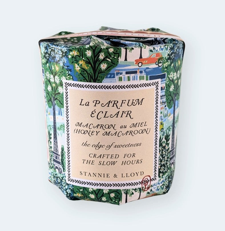 A packaged Stannie & Lloyd La Parfum & Clair Honey Macaron soap bar, wrapped in a detailed Parisian-themed patterned paper with green trees, white flowers, and a red car, featuring a central cream-colored label.