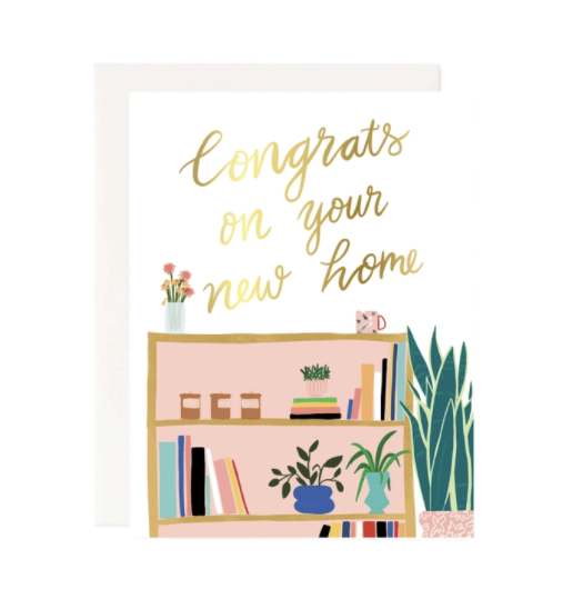 Congrats on Your new home written in cursive with a gold color. Illustration of a bookshelf with books and small plants on it, with a large spider plant next to it and a coffee mug resting on the top shelf