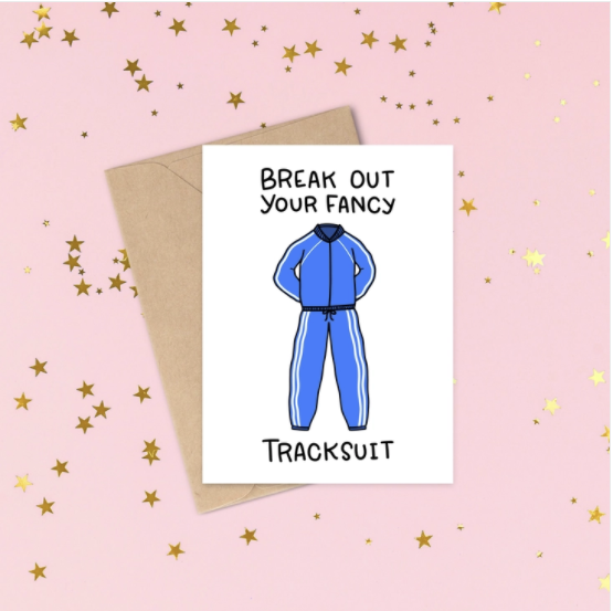 White card with the words written in Black font Break out your fancy tracksuit, with an image of a male track suit jogging suit blue with white stripes down the legs and arms.