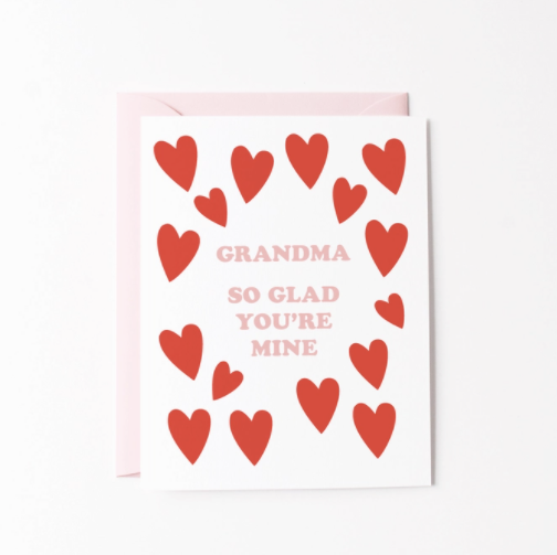 White card with red hearts all around the edges surrounding the words Grandma So Glad You're Mine written in pink.