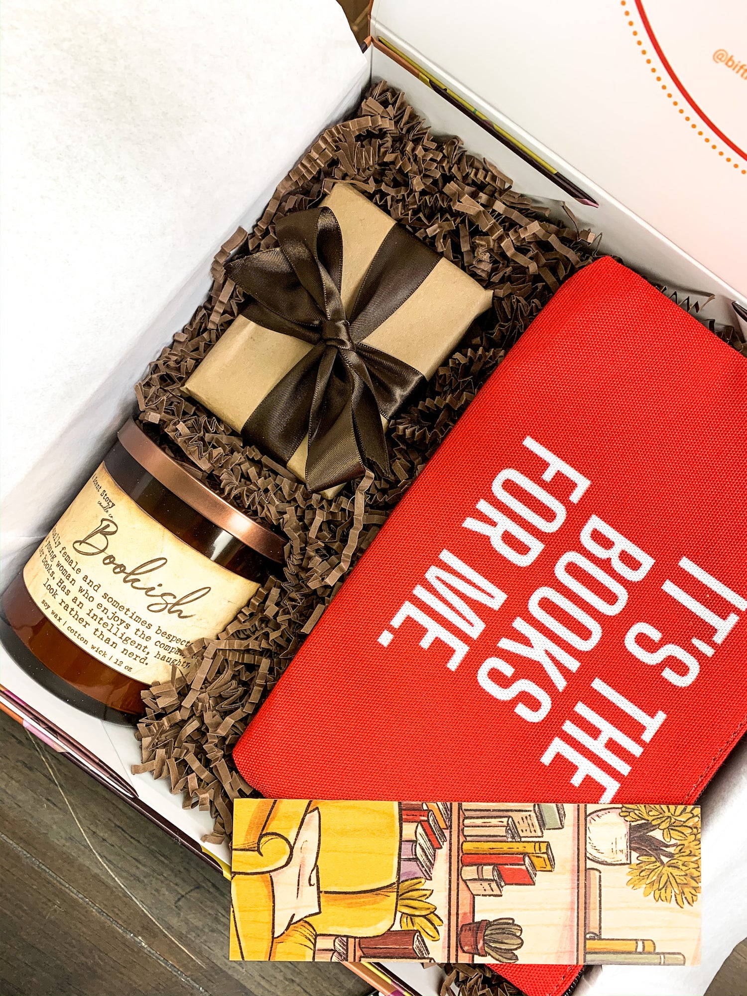 Gift box that includes trivia game cards on Black Authors, a candle titled Bookish and  wooden bookmark and a book pouch in red that reads, "it's the books for me"