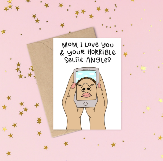 White card with words written in black that say Mom, I love you and your horrible selfie angels. With a picture of someone holding a cell phone and their nostrils and lips take up most of the picture. Great card for mom.