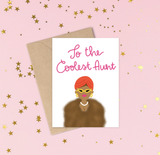 White card with the words To the Coolest Aunt written in pink cursive with a brown skinned woman wearing a fur jacket, pearls, an orange turban and yellow cat eye glasses and pink lip stick. 
